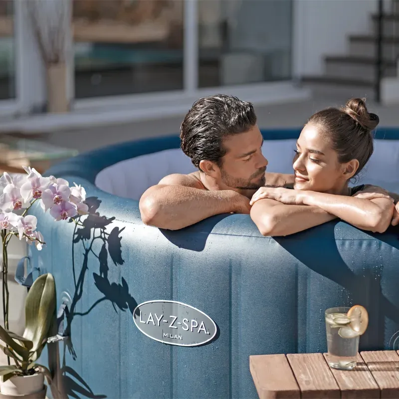 Deux adultes accoudés au rebord du Lay-Z-Spa Milan installé sur une terrasse