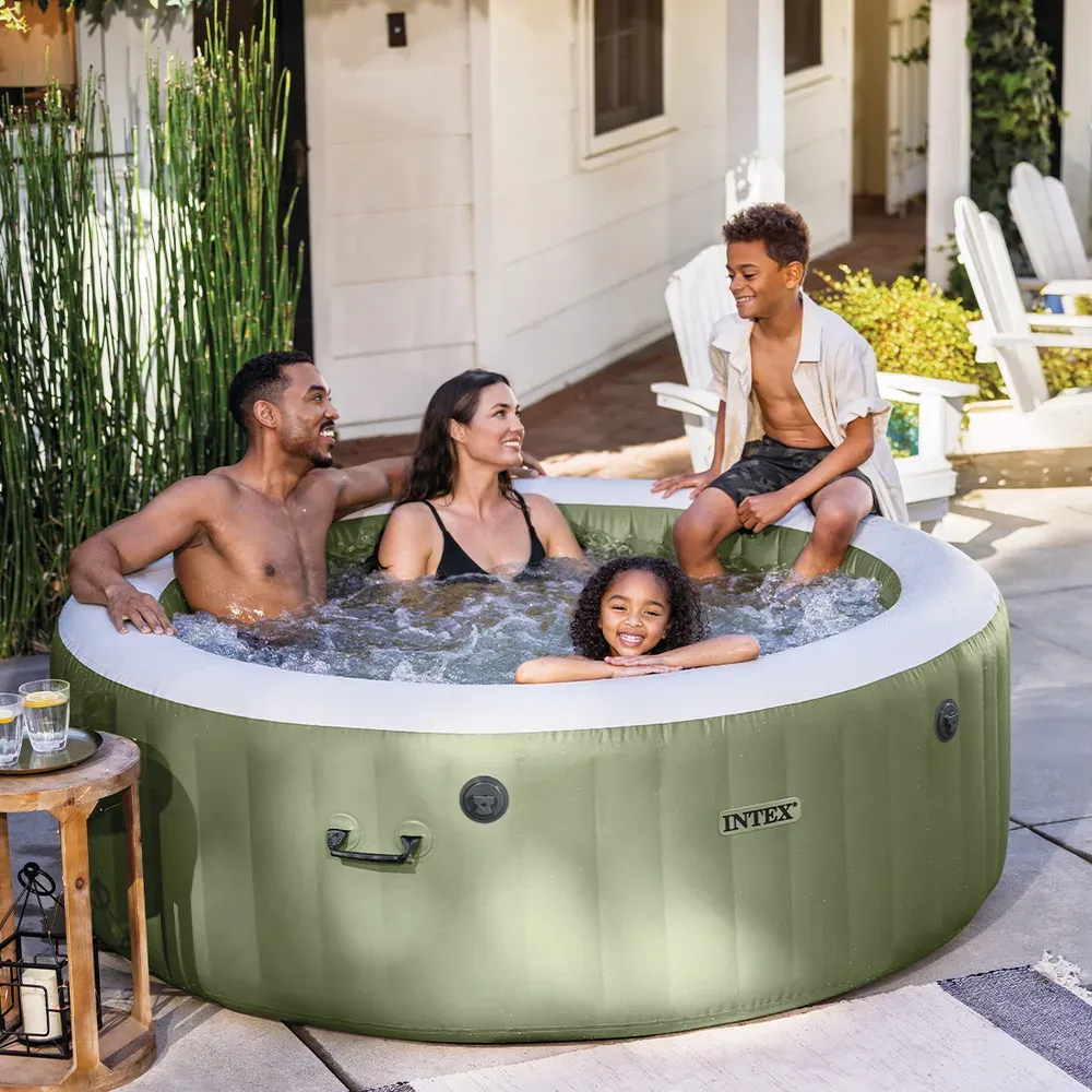Deux adultes et deux enfants installés dans le spa Intex Olive posé sur une terrasse pavée