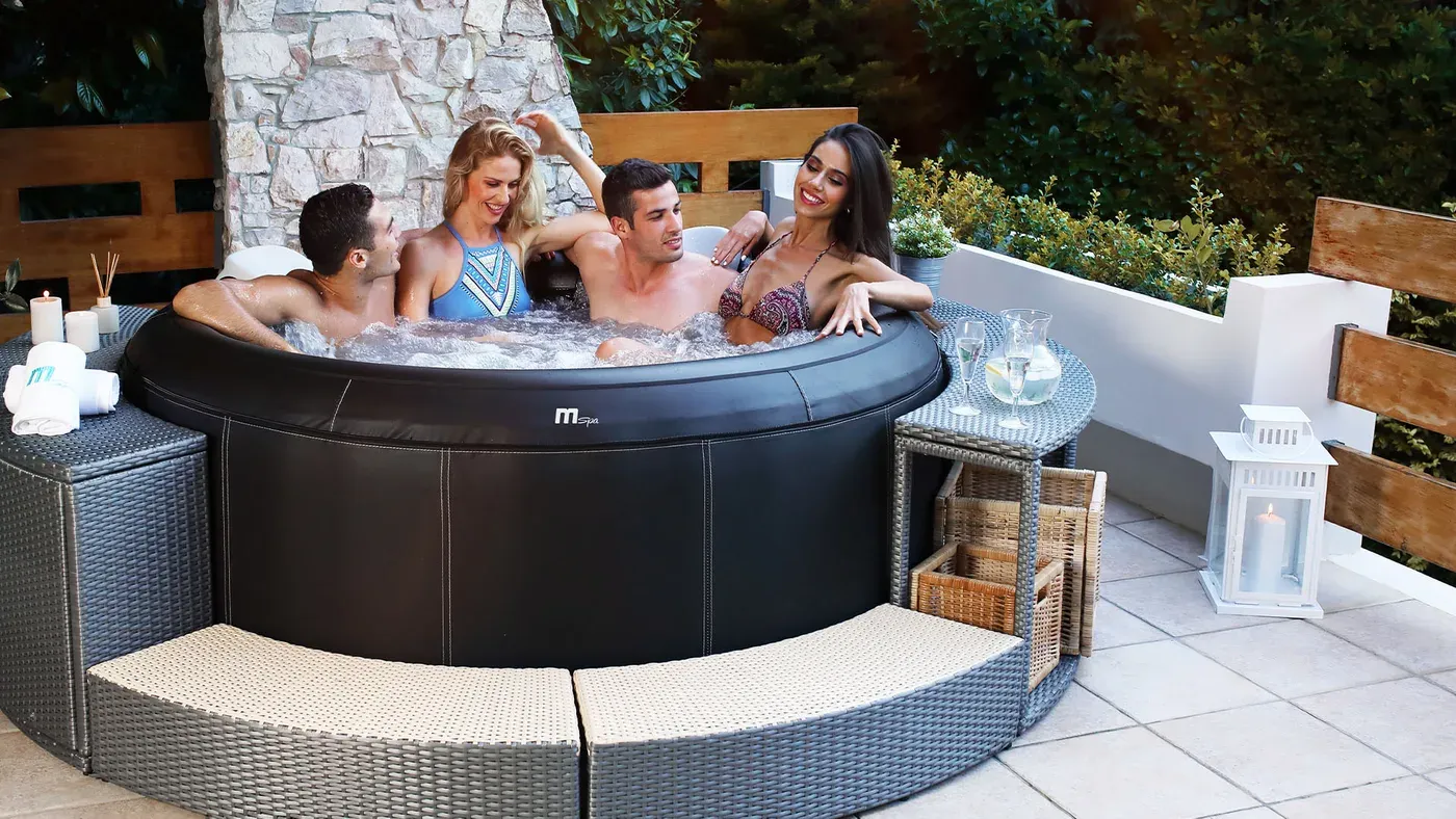 Quatre adultes assis dans le MSpa Camaro installé sur une terrasse carrelée