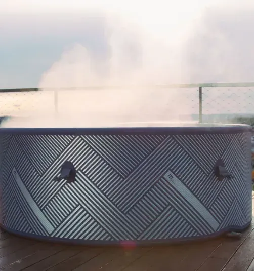 Le spa Naval fumant sur une terrasse en bois, au crépuscule